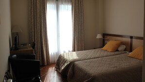 Una habitación de hotel con dos camas, un escritorio con computadora y una silla.