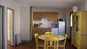 Una cocina compacta con muebles de madera, microondas, refrigerador y una mesa de comedor con sillas.