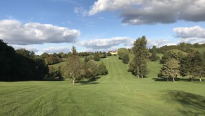 Un campo de golf con cielo despejado y nubes dispersas.
