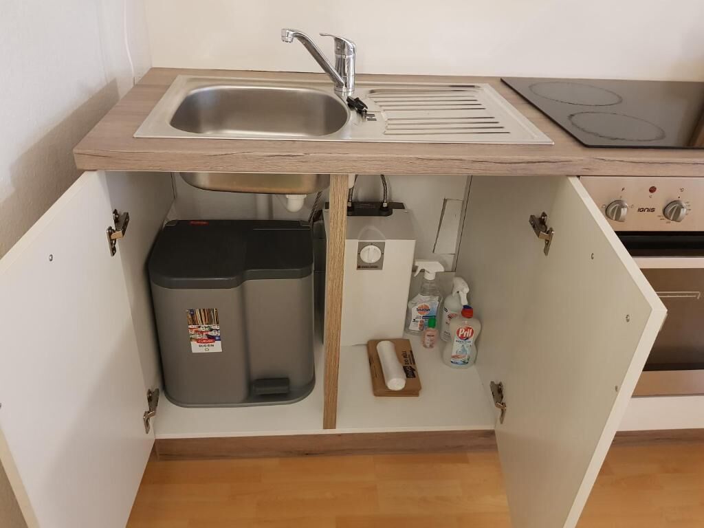 A kitchen with a sink, stove, and storage cabinets.