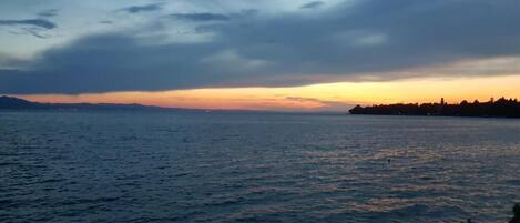 A calm sea at sunset with a distant shoreline.