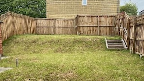 A single-story brick building with a sloped roof, surrounded by a wooden fence. - 2 Bed House - Sleeps 4 - Parking - Wifi (Leeds)