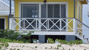 Un edificio a due piani con un balcone, esterno giallo e bianco, e una scala che conduce al piano superiore.