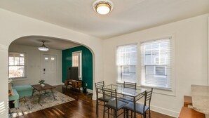 A spacious living room with hardwood flooring, a glass dining table, and a cozy seating area with a teal sofa. - Downtown 2 BR Retreat / Discounts for Longer stays (Indianapolis)