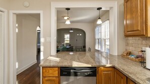 A kitchen with granite countertops, wooden cabinets, and a dishwasher. - Downtown 2 BR Retreat / Discounts for Longer stays (Indianapolis)