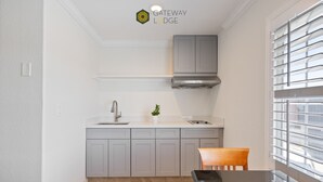 A modern kitchen with grey cabinets, a stainless steel sink, and a window with blinds. - Gateway Lodge (Seaside)