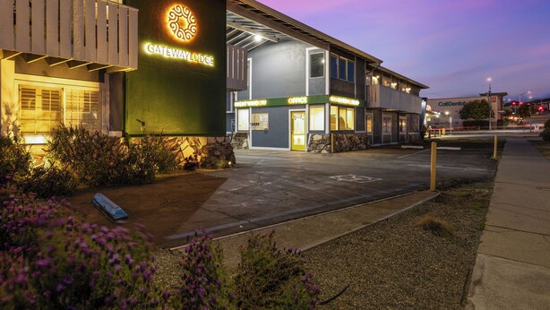 A Gateway Lodge building with a visible entrance, a parking area, and a sign indicating the presence of a dental office. - Gateway Lodge (Seaside)