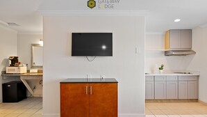 A modern kitchen with a built-in oven, microwave, and a flat-screen TV mounted on the wall. - Gateway Lodge (Seaside)