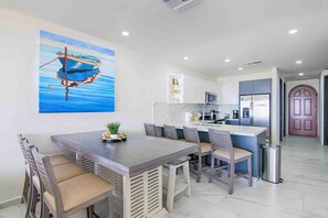 A modern kitchen with a central island, white cabinets, and a stainless steel refrigerator. - Casa Blanca Golf Villas 2 Bedrooms Condo E 707 (Puerto Penasco)