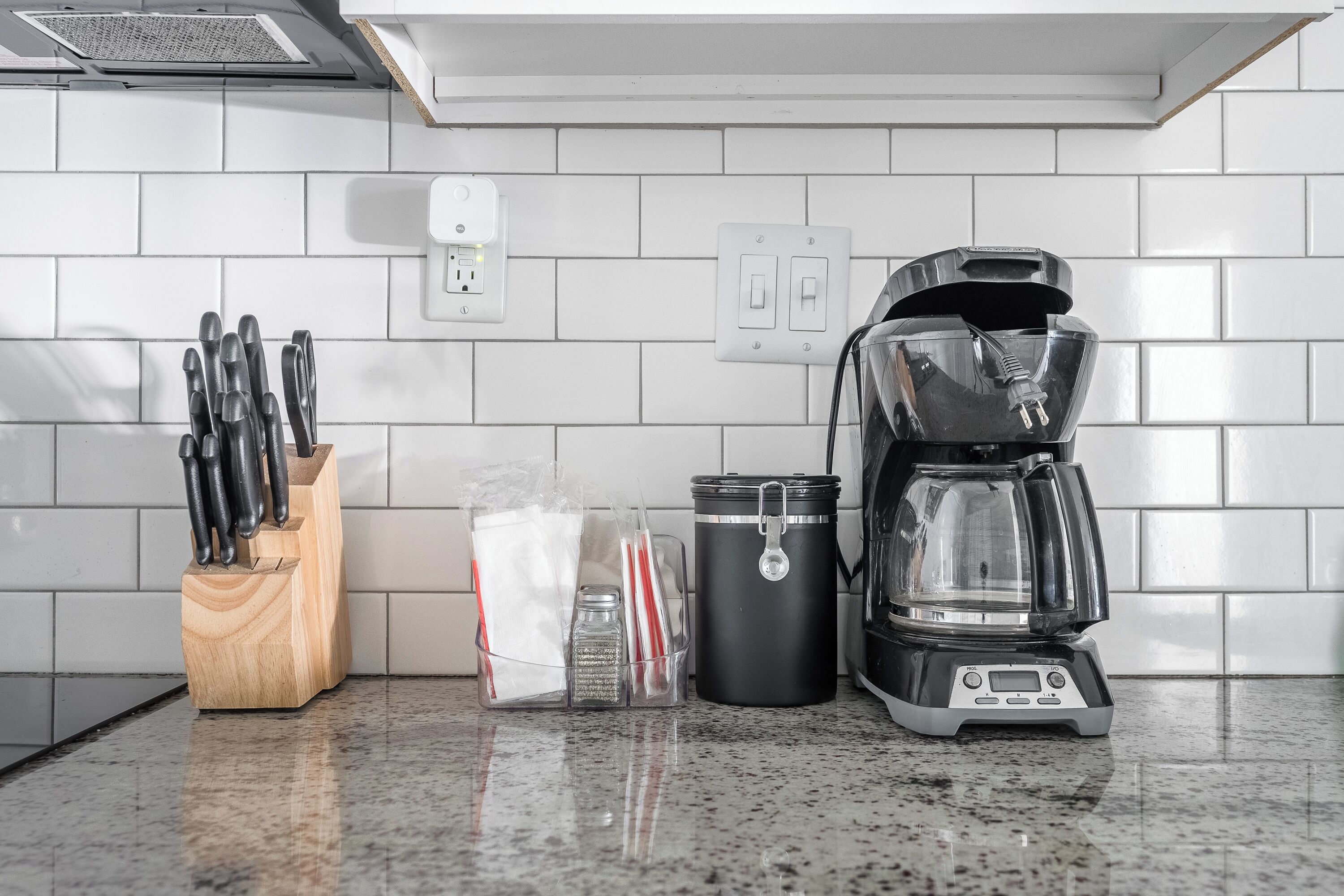 A kitchen counter with a coffee maker, a knife block, and a spice container.