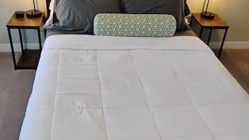 A neatly made bed with a white duvet, two bedside tables with lamps, and a headboard.