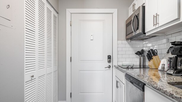 A compact kitchen with white cabinets, a microwave, a coffee maker, and a dishwasher. - The Argyle on Mass Ave (Indianapolis)