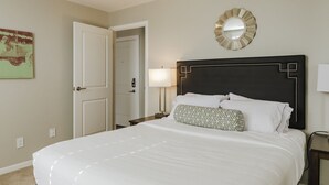 A hotel room with a large bed, a door, a mirror, and a wall-mounted lamp. - The Argyle on Mass Ave (Indianapolis)