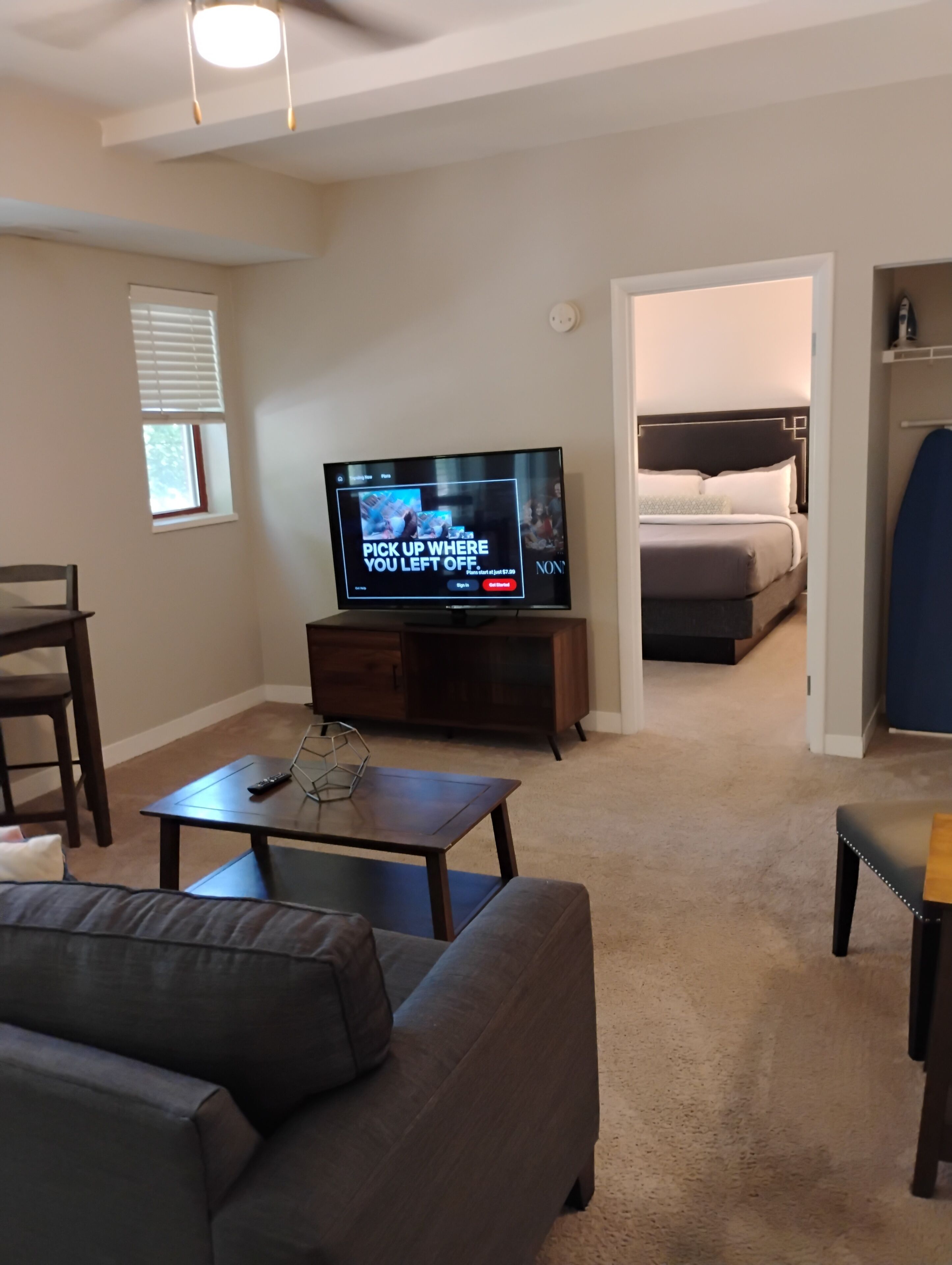 Una sala de estar con televisor, sofá, mesa de centro y comedor.