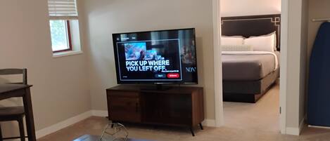 A living room with a television, a couch, a coffee table, and a dining area.