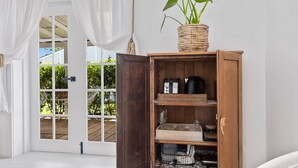 A room with a wooden cabinet, a potted plant, and a view through a glass door to an outdoor area.