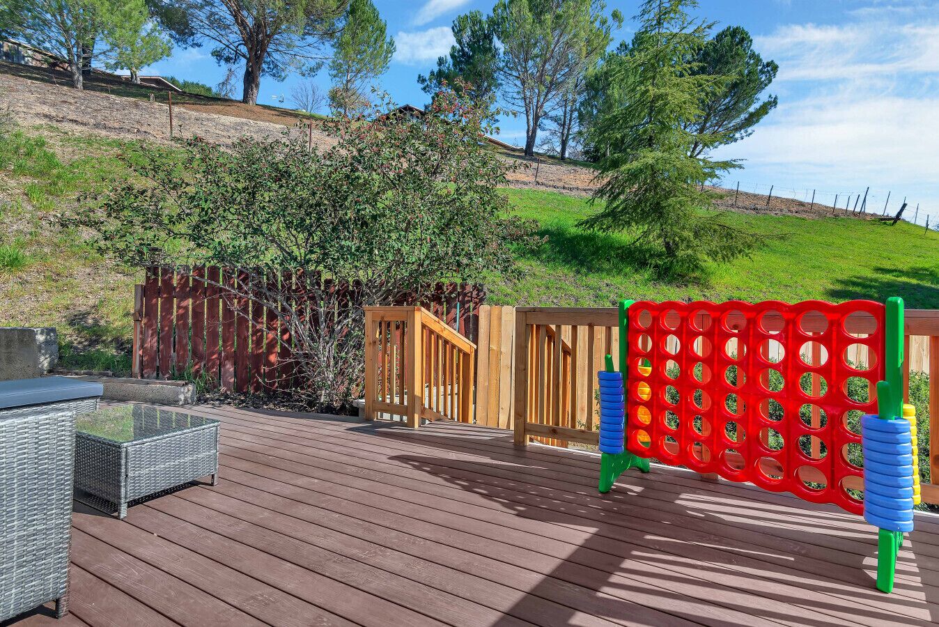 Une terrasse en bois avec des meubles d’extérieur, une porte en bois et une structure de jeu colorée.