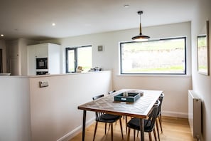 A modern kitchen with a dining table, chairs, and a view of the outdoors. - A llyn peninsula that sleeps 4 guests  in 2 bedrooms (Pwllheli)