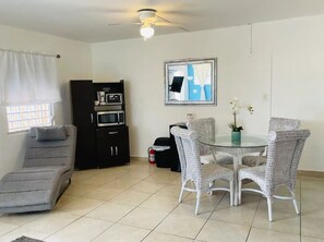 A compact living space with a dining area, a kitchenette, and a gray sofa.