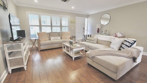A living room with a sofa set, a coffee table, and a TV on a stand.