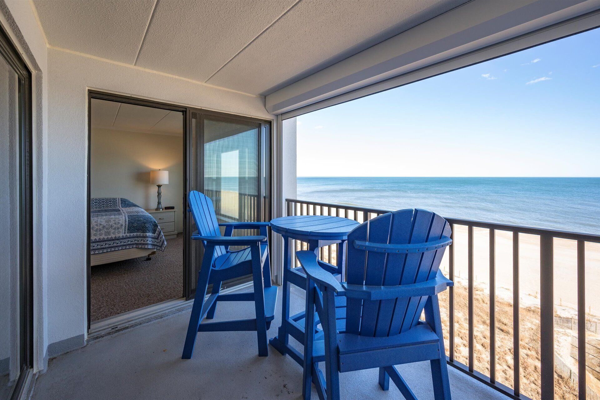Ein Balkon mit Blick auf das Meer, ausgestattet mit einem Bett, einem Tisch und zwei Stühlen.