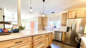 Una cocina moderna con armarios de madera, electrodomésticos de acero inoxidable e iluminación colgante.