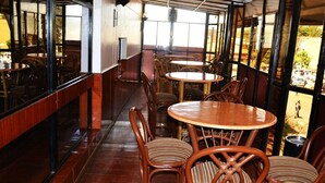 An indoor dining area with wooden tables and chairs, large windows, and a view of the outside. - Cicada Hotel (Eldoret)