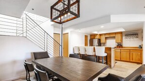 Eine moderne Küche mit Holzschränken, einer zentralen Kochinsel und einem Essbereich mit Holztisch und Stühlen.