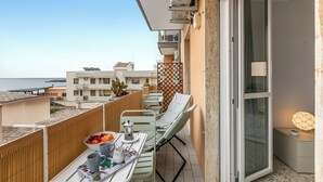 Un balcón con mesa lista para el desayuno, una silla y vista al mar.