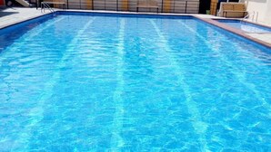A rectangular swimming pool with clear blue water, surrounded by a tiled deck and a low brick wall. - Sizzling Waters Resort (Nakuru)