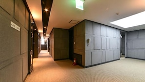 Ein Hotelgang mit Teppichboden, einem Feuerlöscher und einem Telefon an der Wand.