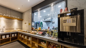 Ein modernes Café mit Marmorplatte, einer Auswahl an Speisen, einem Kühlschrank und einer Kaffeemaschine.