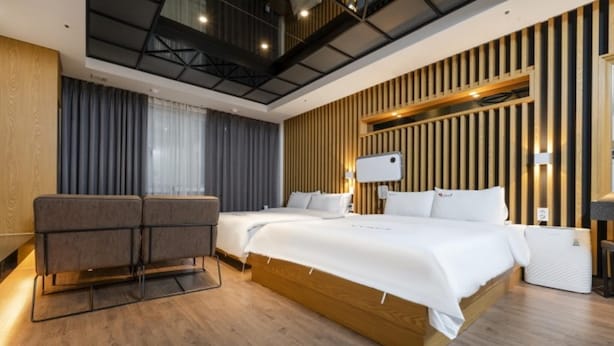 Ein modernes Hotelzimmer mit zwei Betten, einer Sitzecke und einer Wand mit Holzverkleidung.
