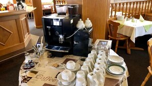 A coffee station with multiple coffee makers, cups, and saucers arranged on a table.