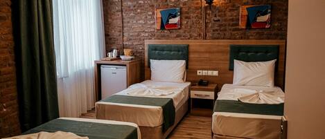 Habitación de hotel con dos camas, un escritorio pequeño, un refrigerador y una pared de ladrillo.