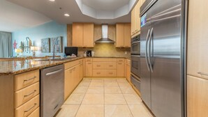 Una cucina moderna con elettrodomestici in acciaio inossidabile, mobili in legno e pavimento piastrellato.