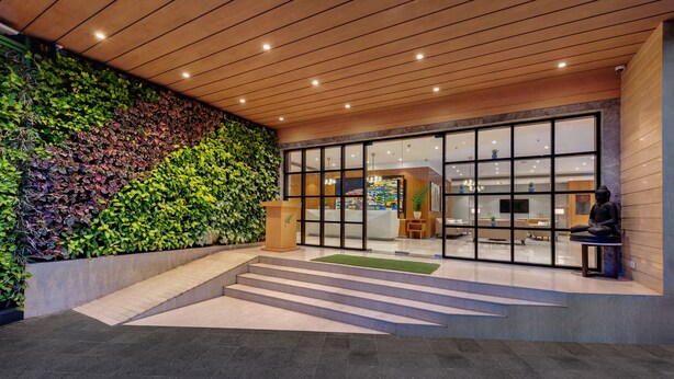 A modern building entrance with a green wall, a reception desk, and a statue. - The Fern Residency Navi Mumbai, Turbhe, Series by Marriott (Navi Mumbai)