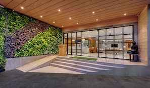 A modern building entrance with a green wall, a reception desk, and a statue. - The Fern Residency Navi Mumbai, Turbhe, Series by Marriott (Navi Mumbai)