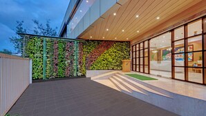 A modern building exterior with a green vertical garden, a tiled patio, and large glass windows. - The Fern Residency Navi Mumbai, Turbhe, Series by Marriott (Navi Mumbai)