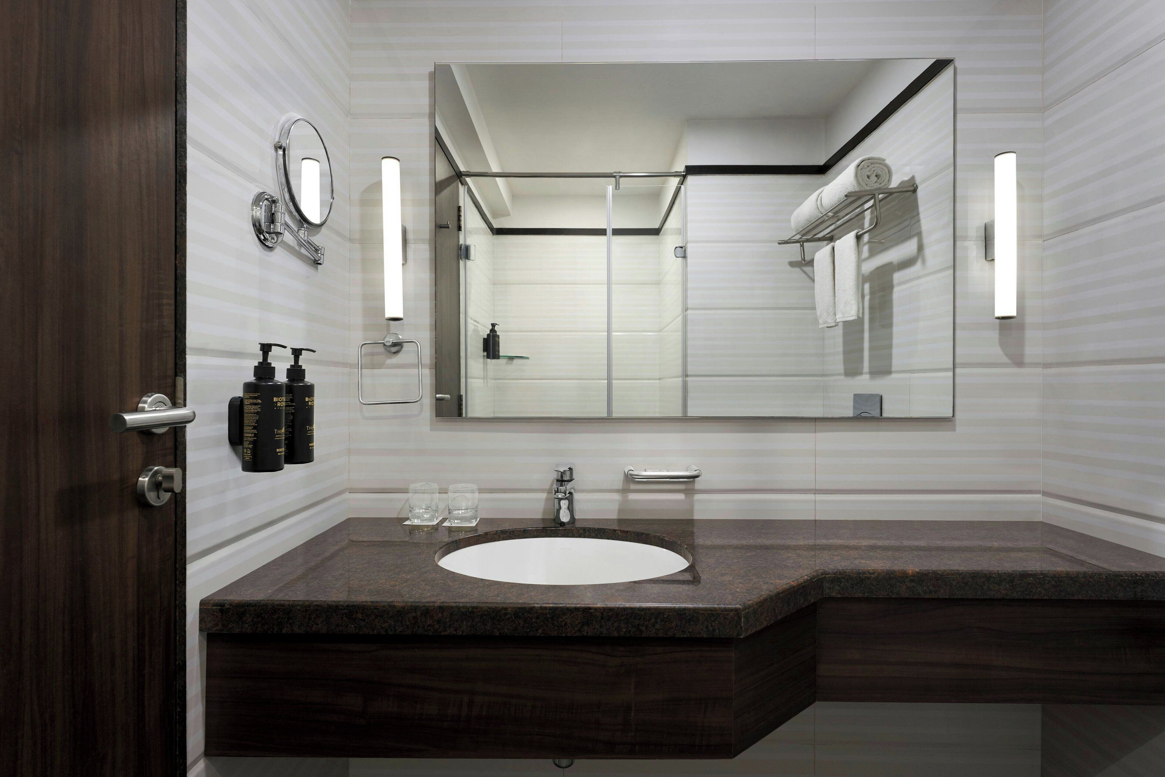 A modern bathroom with a large mirror, a sink, and a shower area.