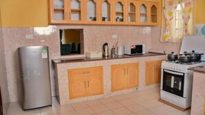 Une cuisine équipée d’un réfrigérateur, d’un four à micro-ondes, d’une cuisinière et de meubles de rangement en bois.