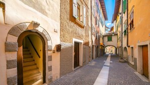 Un estrecho callejón adoquinado con edificios a ambos lados, una escalera que lleva a un nivel superior y un pequeño puente sobre la calle.