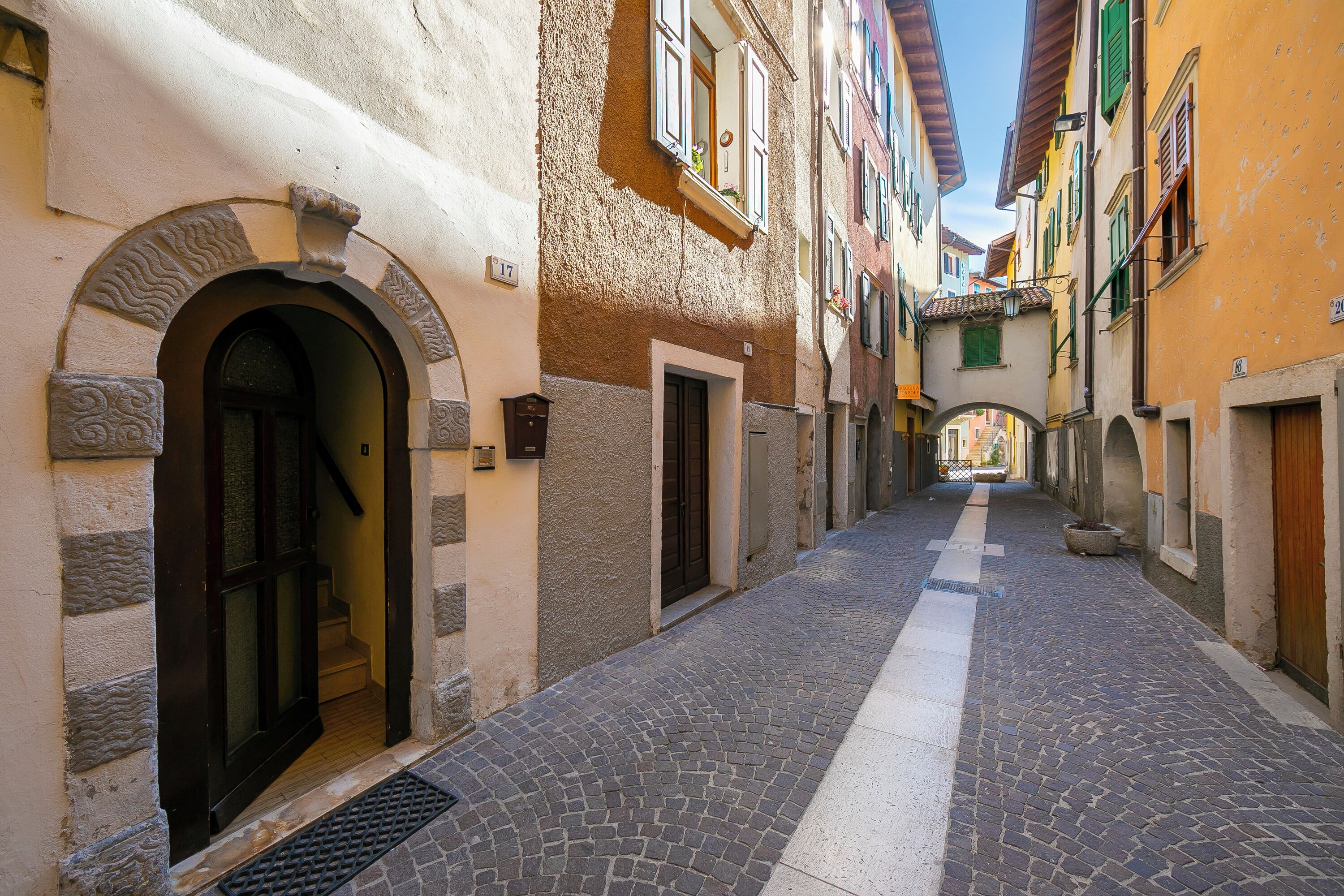 Una estrecha calle empedrada bordeada por edificios con puertas y ventanas de arco.