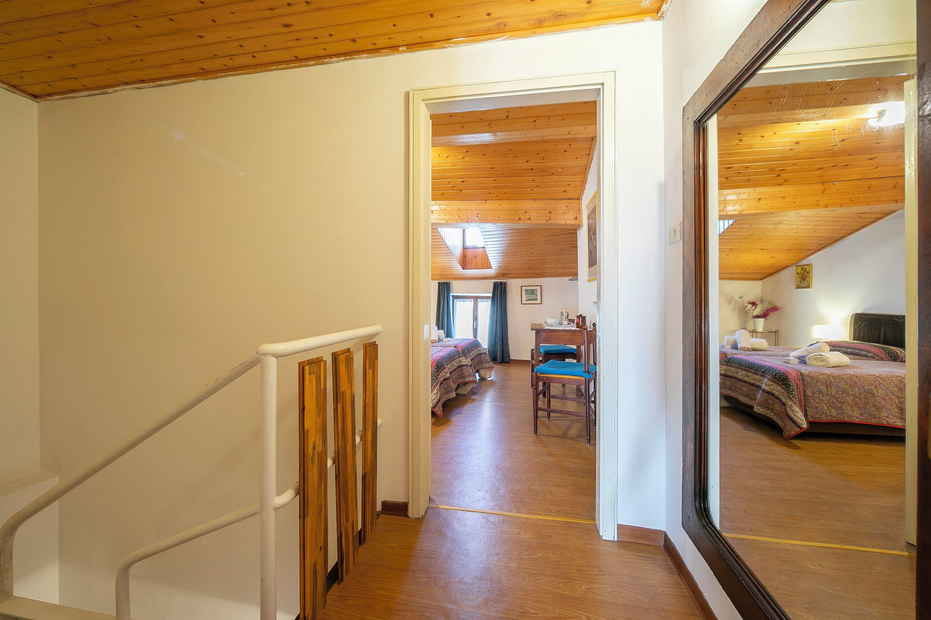 A hallway leading to a bedroom with a wooden ceiling, a desk, and a chair.