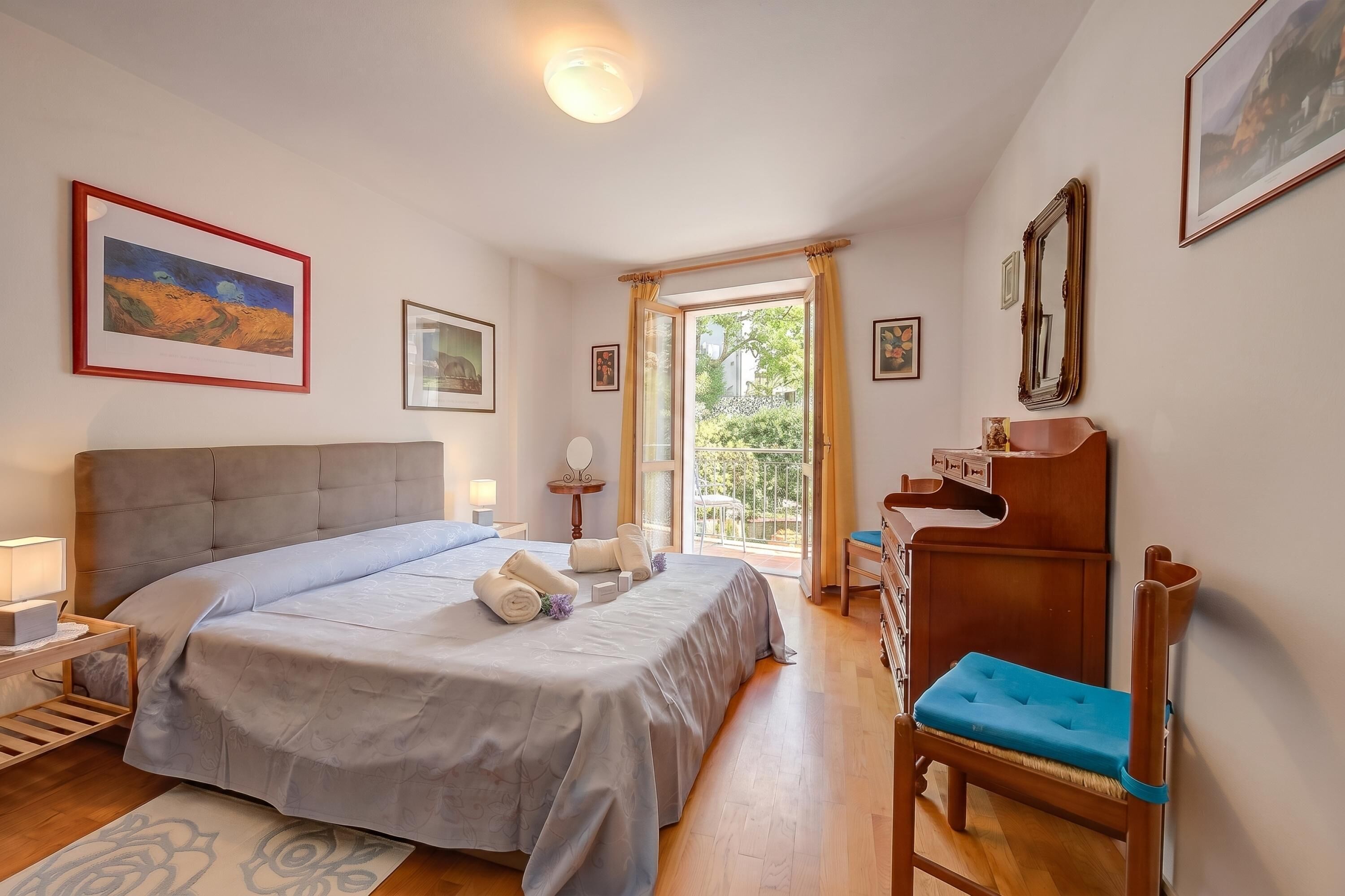 Une chambre bien rangée, avec un lit, des tables de chevet, une chaise et une vue sur l’extérieur.