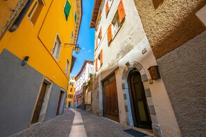 A narrow street with buildings on either side, featuring a mix of architectural styles and a cobblestone path.