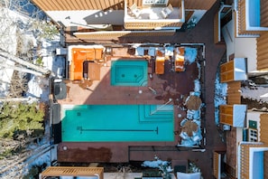 A rooftop pool area with a pool, lounge chairs, and a wooden deck.