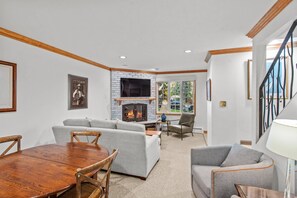 Cozy living room with a central fireplace, two sofas, and a dining table.