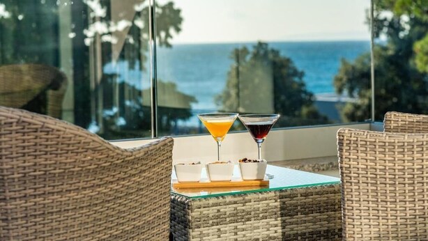 Ein Balkon mit Korbmöbeln, zwei Martini-Gläsern und Schalen mit Essen.