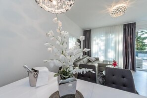 A modern living room with a white orchid centerpiece, a chandelier, and a view of the outdoors through large windows. - Sunset apartment with private pool and jacuzzi  (Novalja)
